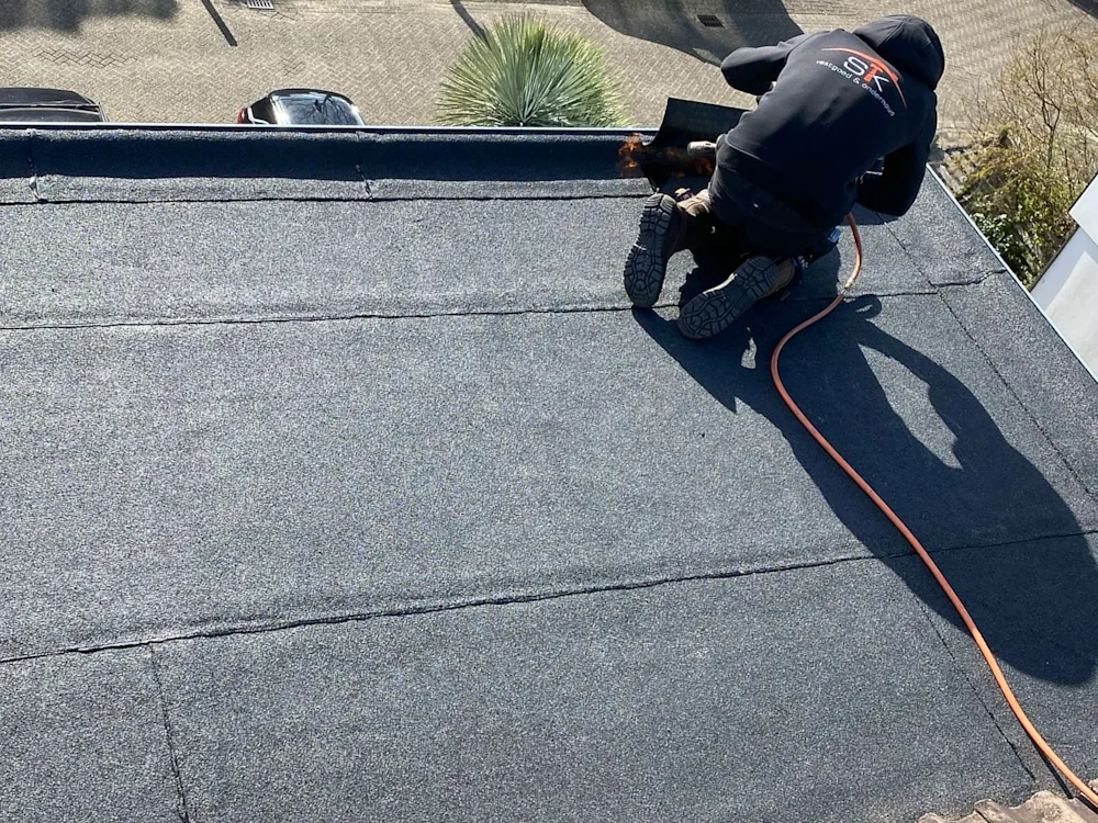 dakdekker aan branden op een bitumen dak